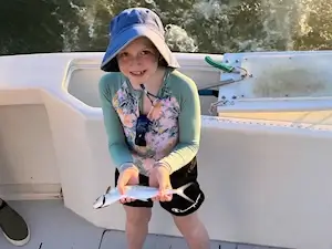 Cute young lady vacationing in kill devil hills holds up a spanish mackerel she caught on a near shore charter trip.