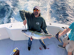 Gentleman angler struggles to hold up a massice yellowfin tuna caught on his offshore charter.